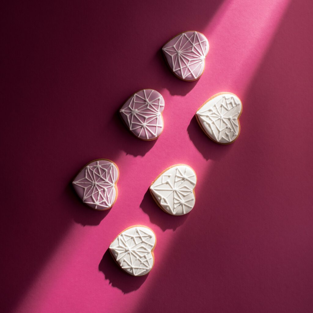 top view of glazed heart shaped cookies on pink tabletop