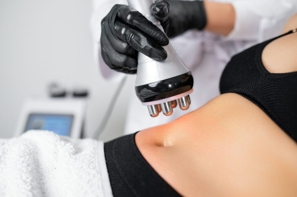 RF body cavitation lifting procedure to reduce fat in belly to young woman in a beauty salon.